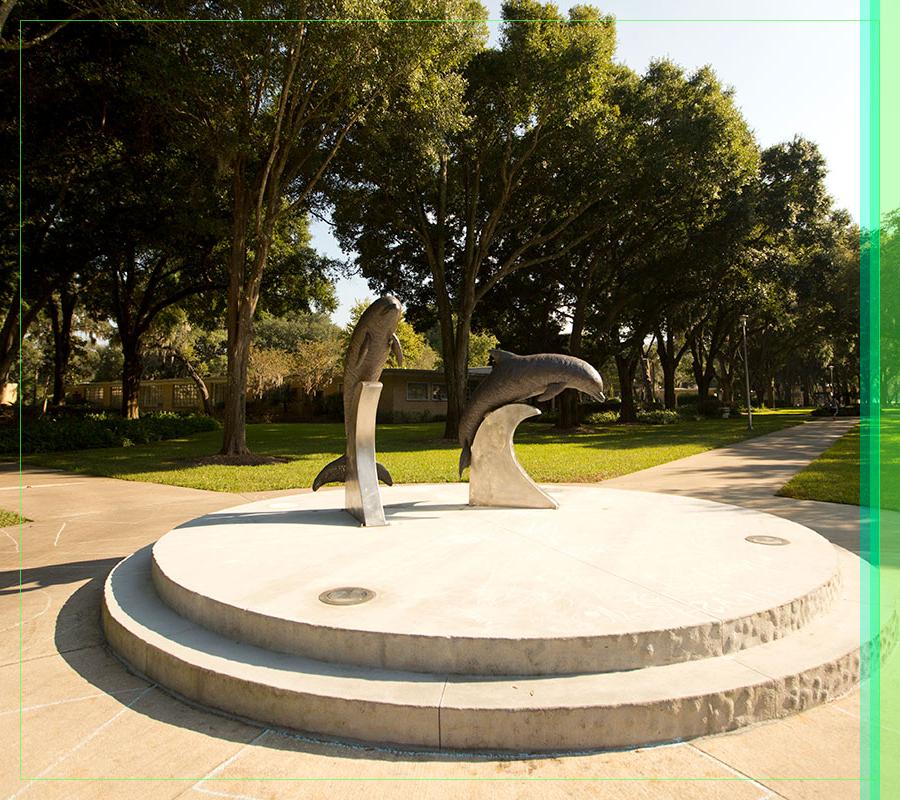 A sunlit picture of the dolphin statues behind the 如何ard Administration Building.